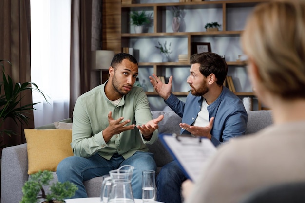 A family psychologist conducts a session in a beautiful office LGBT couple at a psychotherapist's appointment Psychologist for gays Support for the LGBT community in visiting a psychologist