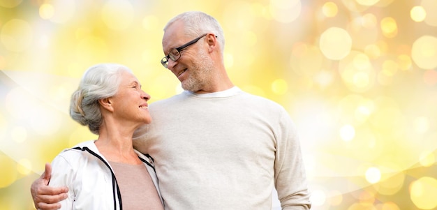 family, relations, age and people concept - happy senior couple over holiday lights background