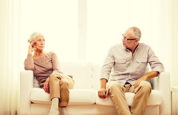 family, relations, age and people concept - senior couple sitting on sofa at home