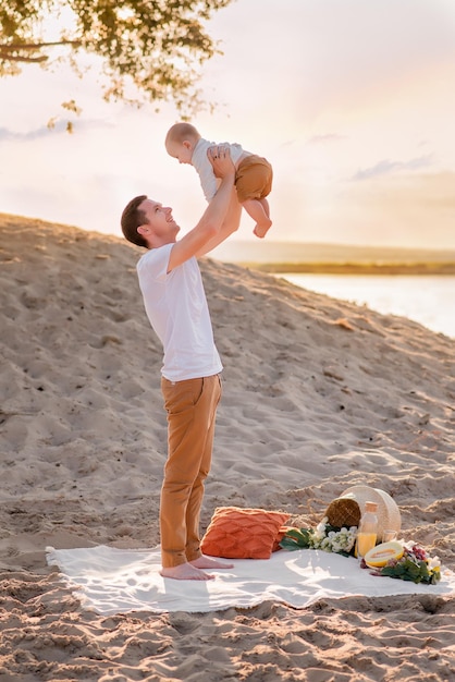 Family resting on a picnic on the beach near the sea ocean mother and father are holding a child a happy family