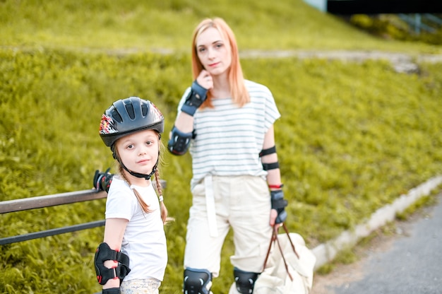 Family rollerskating in park. Active walk. Preschool girl having active walk with her mother