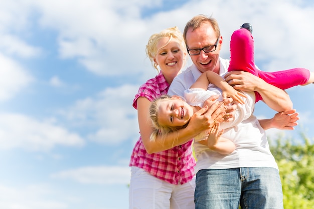 Family romping on field with parents carrying child