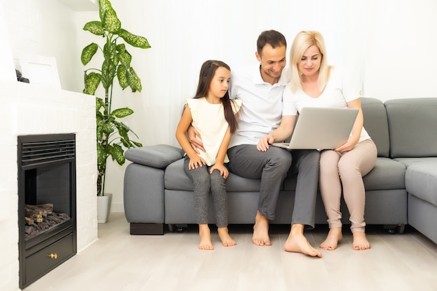 Family shopping online. Happy family smiling while sitting on the couch and shopping online together