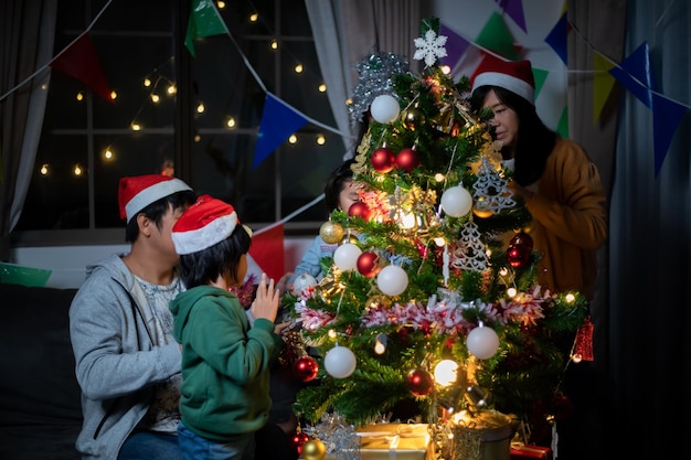 Family and siblings enjoying Christmas time and children is decorating Christmas tree