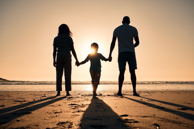 Family silhouette at the beach holding hands at sunset and people with love care and support outdoor Mom dad and kid travel back and ocean view with parents and children outdoor in nature