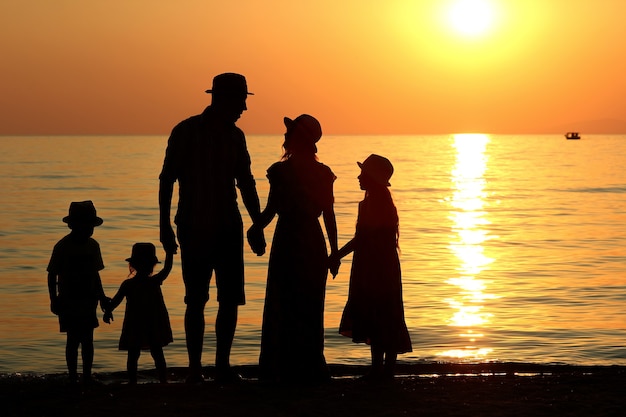 Family silhouette at sunset by the sea in summer