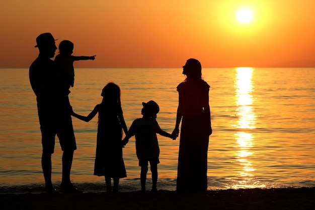 family silhouette at sunset by the sea in summer