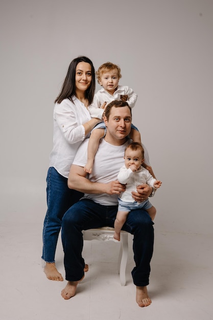 A family sits on a white chair with their baby on the right side.