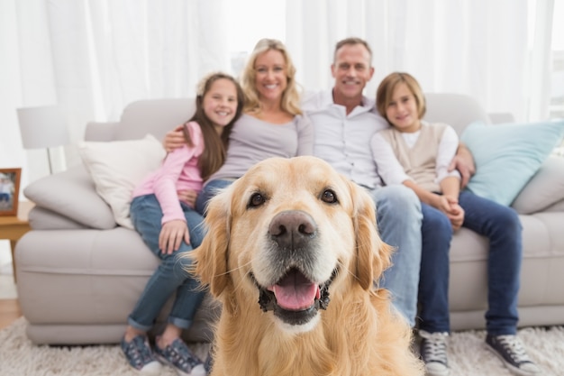 Family sitting on the couch with golden retriever in foreground