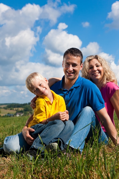 family sitting in grass on meadow