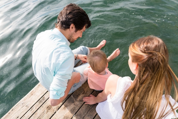 Family sitting on water hanging feet in the pond, view from above