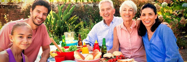 Family smiling at camera while having meal outdoors