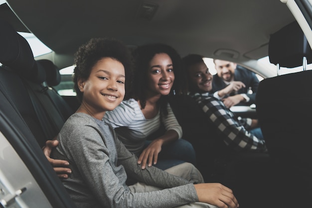 family smiling sitting in a car