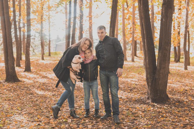 Family spend time in autumn park with a dog. Father, mother and daughter and jack russell terrier dog having fun in fall