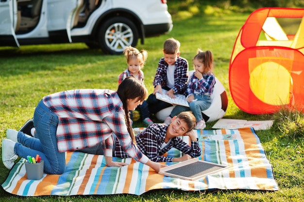 Family spending time together Mother with four kids outdoor in picnic blanket and kids tent