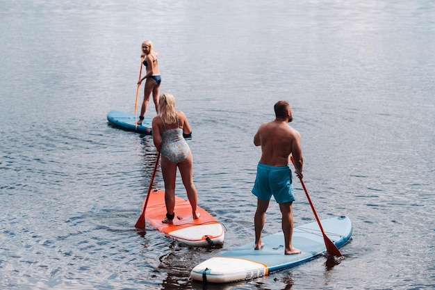 The family spends time together swimming on sup boards on the lake