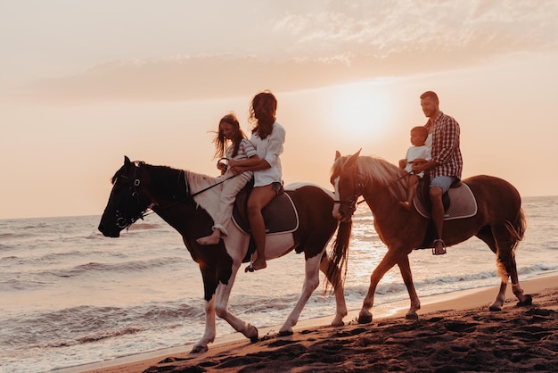 The family spends time with their children while riding horses together on a sandy beach. Selective focus. High quality photo