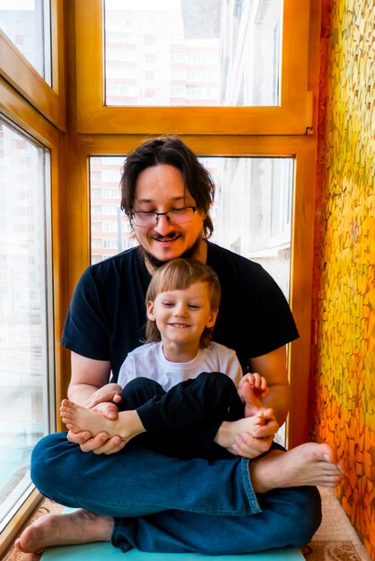 Family sport father teaches son to do exercises In a home apartment