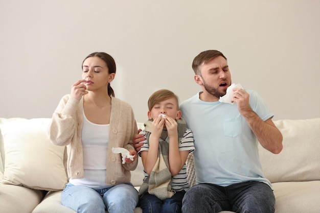 Family suffering from runny nose on sofa at home