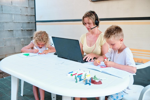 A family in a summer camping where the mother is working and the children are drawing