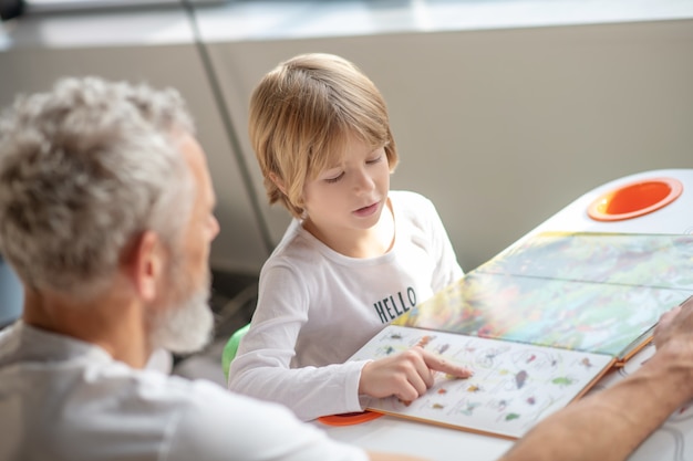 Family support. A boy reading an interesting book together with his father