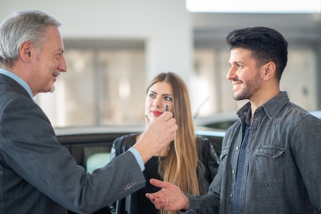 Family talking to the salesman and choosing their new car in a showroom