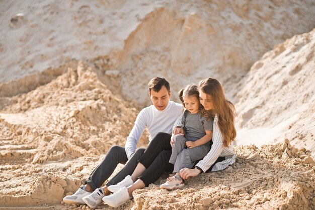 A family of three is sitting among mountains of sand 3350