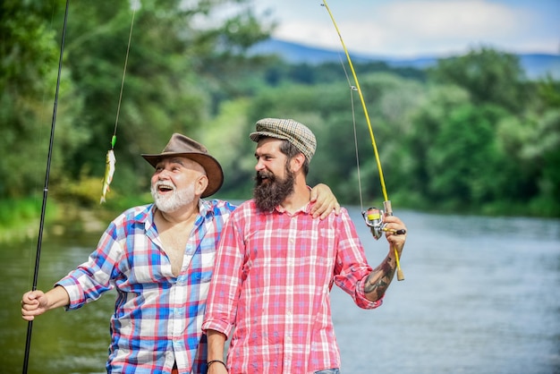 Family time Activity and hobby Fishing freshwater lake pond river Mature man with friend fishing Summer vacation Happy cheerful people Fisherman with fishing rod Bearded men catching fish