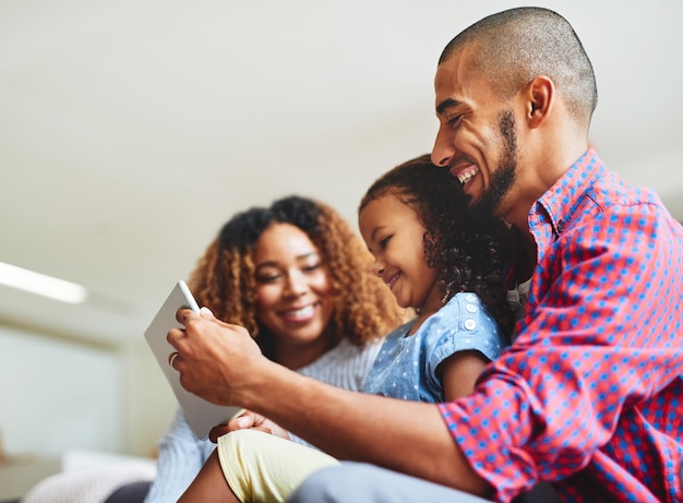 Family time and screen time combined Shot of an adorable little girl and her parents using a digital tablet together on the sofa at home