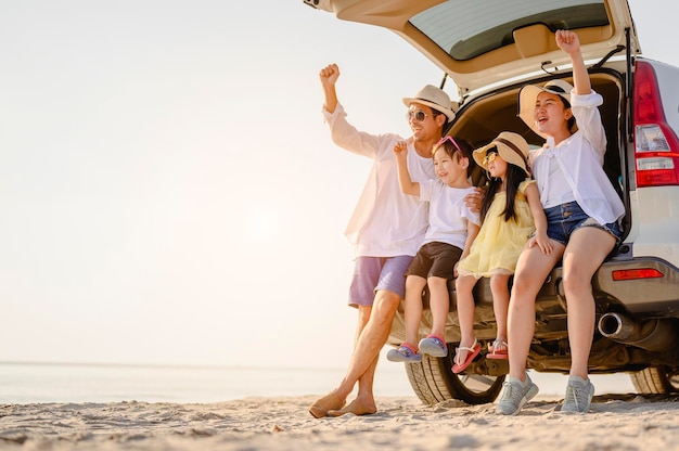 Photo family, travel, beach, relax, lifestyle, holiday concept. family who enjoy a picnic sitting in the back of the car on the beach at sunset in holiday.