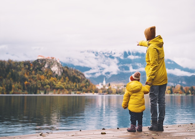 Family Travel Europe Mother and child in yellow raincoats looking at Bled Lake Slovenia