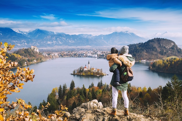 Family travel Europe. Mother with son looking on Bled Lake. Autumn or Winter in Slovenia, Europe. Top view on Island with Catholic Church in Bled Lake with Castle and Mountains in Background.