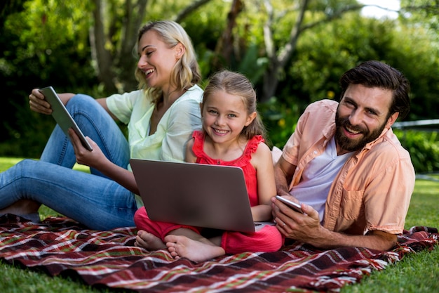 Family using technologies relaxing in yard