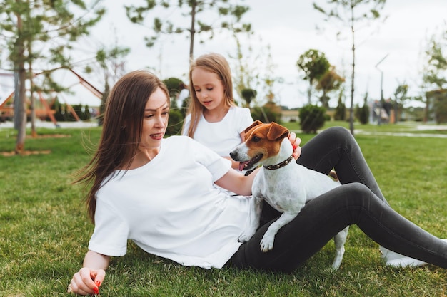 Family walk in the autumn park Outdoor entertainment Mother and daughter walk the dog on a sunny warm autumn day a child plays with a jack Russell terrier in the park