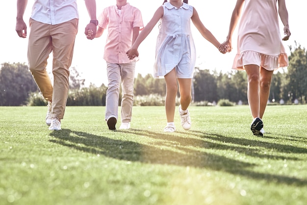 Family walk family of four walking on grassy field legs closeu