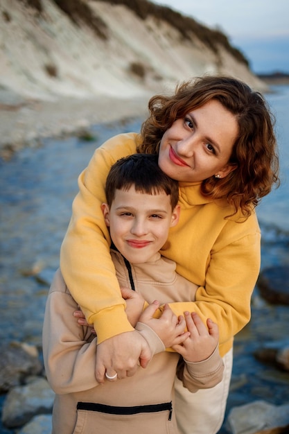 Photo family walk on the seashore in the cold season happy mother and son hugging each other