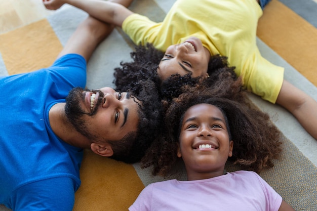 Family weekend Smiling black mother father and daughter lying on bed together relaxing at home