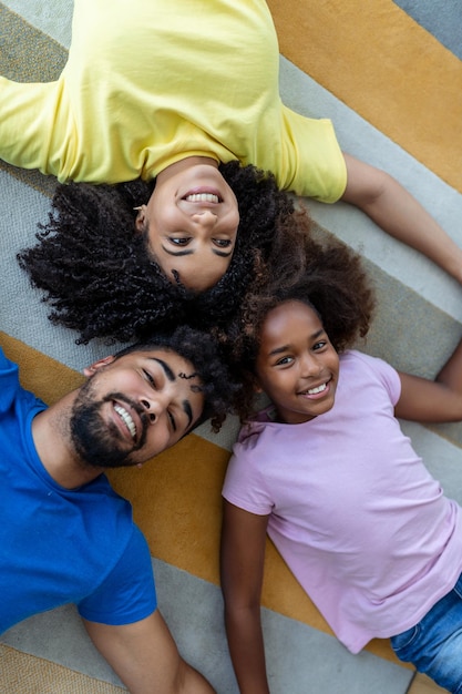 Family weekend Smiling black mother father and daughter lying on bed together relaxing at home