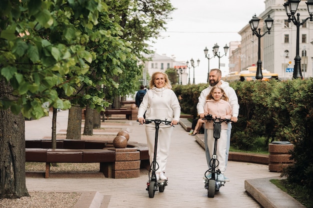 A family in white clothes rides electric scooters in the city.Outdoor activities.