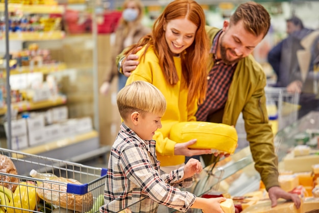 Family with child boy in grocery store, family in shop. Parent and children in a mall choosing meal. Healthy food.