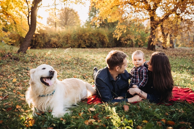 Family with a child and a golden retriever in an autumn park