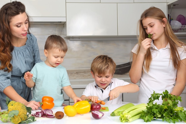 Family with children cut vegetables for cooking
