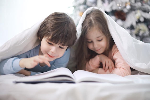 A family with children having fun on the bed under the covers during the Christmas holidays