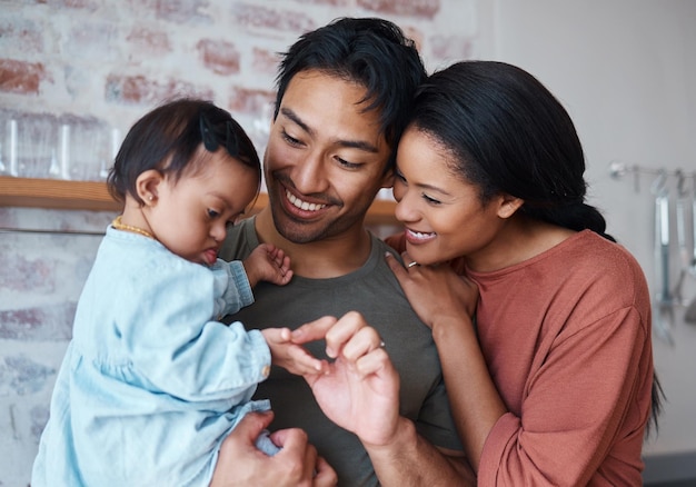 Family with down syndrome baby happy parents in kitchen home together and young child care Indian father holding cute kid asian mother smile with support and bonding happiness in Brazil house