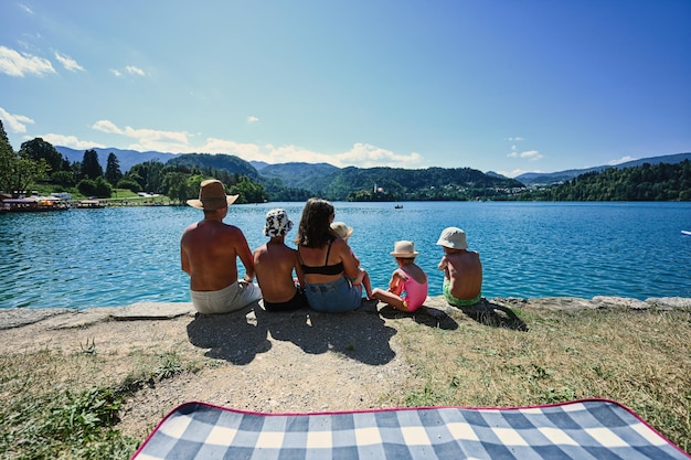 Family with four kids sit in pier of view beautiful Bled Lake Slovenia Parents of many children