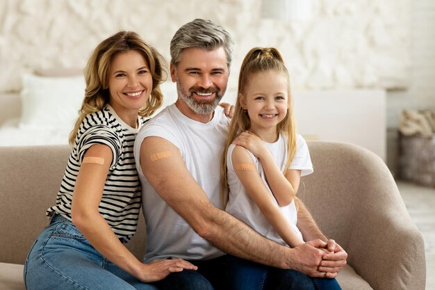 Family with kid showing vaccinated arms with plaster at home