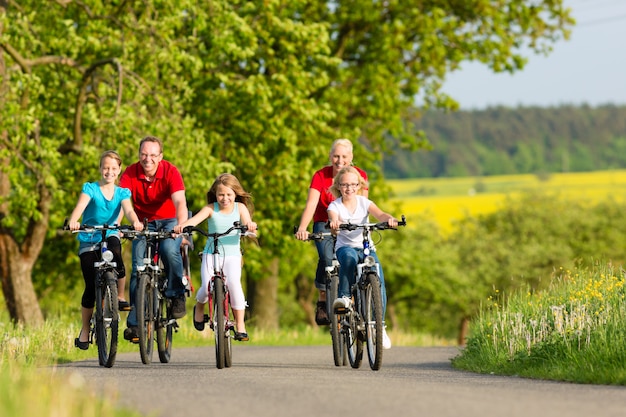 Family with kids cycling in summer with bicycles