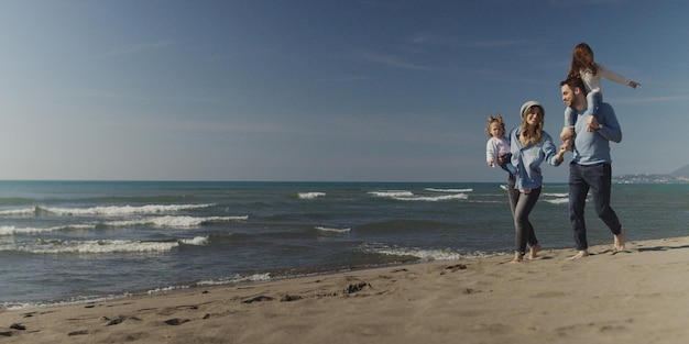 Family with kids resting and having fun at beach during autumn day