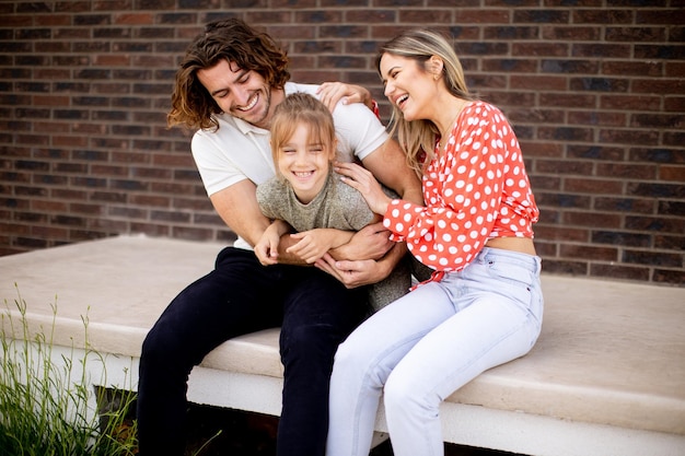 Photo family with a mother father and daughter sitting outside on steps of a front porch of a brick house