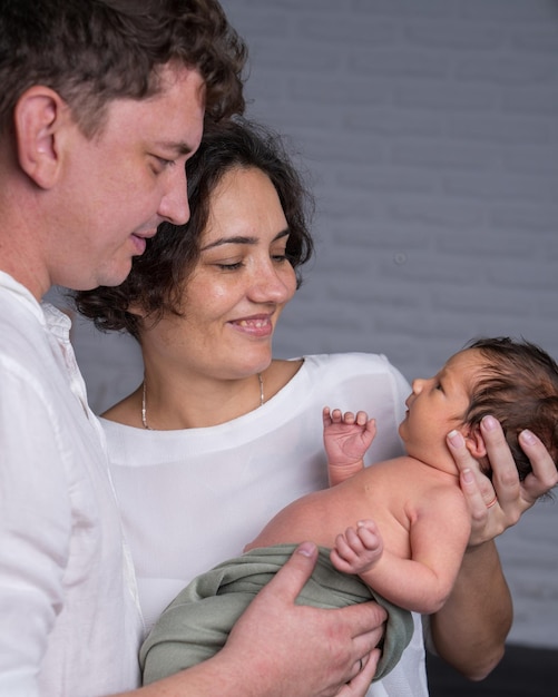 family with a newborn baby Mom and dad hold the baby in their arms and look at their son